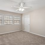 Bright, cozy bedroom with plush carpet, modern ceiling fan, and large windows offering natural light.