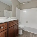 Elegant bathroom featuring modern fixtures, a sleek vanity with rich wood cabinetry, and a pristine white tiled bathtub, exuding contemporary charm.