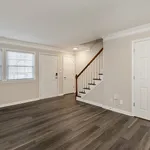 Inviting entryway with elegant wood flooring and a staircase, ample natural light through large windows, and modern neutral decor.