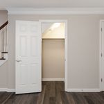 Inviting apartment featuring a modern closet with elegant flooring and a sleek staircase detail.