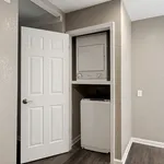 Compact laundry nook featuring a stacked washer and dryer in a modern apartment with sleek wood flooring.