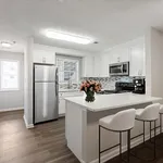 Bright contemporary kitchen with stainless steel appliances, sleek white cabinetry, and a cozy breakfast bar adorned with fresh flowers.
