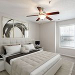 Bright and modern bedroom featuring a plush bed with elegant decor, large window for natural light, and ceiling fan for comfort.