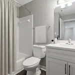 Elegant bathroom with modern fixtures, featuring a sleek vanity, pristine tub, and stylish decor.