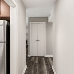 Chic apartment hallway with modern wood flooring and sleek stainless steel kitchen appliance.