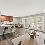 Bright and modern open-plan living area with stylish kitchen, cozy dining nook, and elegant decor, leading to a sunlit balcony.