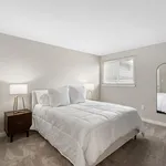 Bright and cozy bedroom featuring a plush bed with white bedding, modern bedside lamps, and a large mirror reflecting natural light.