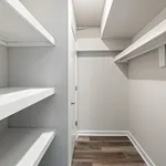 Bright and inviting walk-in closet with sleek white shelving and modern flooring, perfect for organized storage.