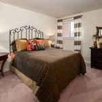 Cozy bedroom with elegant wrought iron headboard, inviting decor, and natural light from a window with striped curtains.