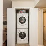 Elegant apartment features a sleek stackable washer and dryer in a compact laundry nook, offering convenience and style.