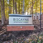 Inviting sign for Biscayne Apartment Homes set amid a serene wooded landscape, offering tranquil living in a picturesque setting.
