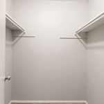 Spacious walk-in closet with neutral tones and ample shelving, ideal for stylish storage solutions.