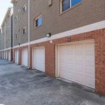Modern townhouse exterior featuring multiple garages and brick facade, offering ample parking and stylish urban living.