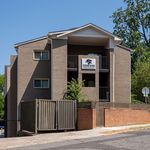Charming Cedar Oaks Condominiums building exterior with modern brick facade and inviting balconies surrounded by lush greenery.