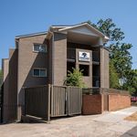 Modern Cedar Oaks condominium building with stylish brick exterior and spacious balconies, nestled amidst vibrant greenery.