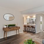Inviting open-concept living space with stylish decor, hardwood floors, and a modern breakfast bar leading to a sleek kitchen.