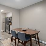 Contemporary dining area with a sleek wooden table, stylish chairs, and a view into a modern kitchen with stainless steel appliances.