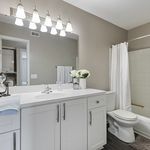 Bright and modern bathroom with elegant white cabinetry, sleek countertop, and soft lighting, offering a luxurious experience.