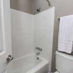 Modern bathroom featuring a pristine white bathtub, elegant tiled walls, and a sleek towel rack.
