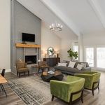 Elegant living room featuring a vaulted ceiling, stylish chandelier, and a cozy fireplace, complemented by plush seating and contemporary decor.