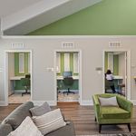 Chic apartment lounge with vibrant green accents, featuring cozy workspaces and stylish seating.
