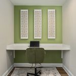 Modern home office nook with green accent wall, stylish lattice decor, and sleek workspace setup.
