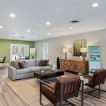 Elegant living room with modern sofa, stylish armchairs, and chic wooden sideboard, enhanced by soft ambient lighting and a fresh green accent wall.