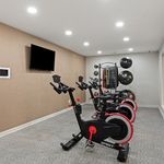 Modern fitness room equipped with stationary bikes, a sleek wall-mounted TV, and versatile exercise gear for a dynamic workout experience.