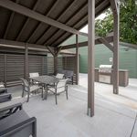 Charming outdoor patio with modern seating and a sleek barbecue grill under an elegant pergola.