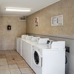 Bright and spacious laundry room with modern washing machines and tiled walls, offering a convenient and clean space for residents.