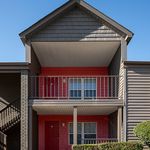 Charming two-story apartment exterior with vibrant red accents, private balconies, and inviting architectural design.