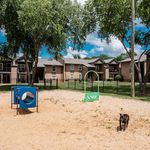 Charming apartment complex with a lush green landscape and a fun sandy playground, perfect for families and pet-friendly living.