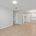 Bright open-concept living space with modern tiled flooring, leading to a cozy kitchen area with ample natural light.