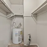 Spacious laundry room with built-in shelves and modern water heater, ideal for organizing and utility needs.
