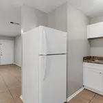 Bright kitchen with modern white refrigerator, sleek cabinetry, and elegant tiled flooring.
