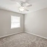 Bright and airy bedroom with plush carpeting, neutral walls, and a ceiling fan, offering a cozy and inviting atmosphere.