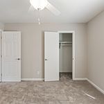 Bright bedroom with soft carpeting, neutral walls, and a spacious walk-in closet, perfect for modern living.