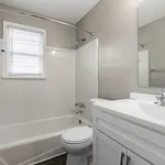 Bright and modern bathroom with sleek fixtures, a pristine white bathtub, and natural light streaming through a window.