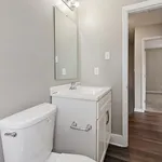 Elegantly designed bathroom featuring a sleek white sink vanity, mirror, and modern fixtures, leading to a cozy carpeted room.