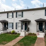 Charming brick townhouse with inviting entrance, featuring classic shutters and a cozy porch, ideal for modern living.
