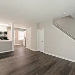 Modern open-concept living space with elegant hardwood floors, neutral walls, and a bright kitchen featuring stainless steel appliances and abundant natural light.