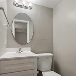 Modern bathroom featuring sleek white vanity with an oval mirror, elegant lighting, and contemporary finishes.