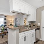 Chic open kitchen design with sleek white cabinets and modern appliances, seamlessly connecting to a cozy living space.