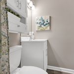 Elegant bathroom with modern fixtures, featuring a chic vanity, stylish wall art, and sophisticated lighting.