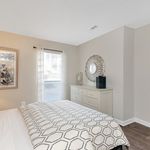 Inviting bedroom with stylish decor, featuring a plush bed, elegant dresser, and bright natural lighting through a large window.