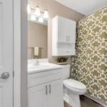 Elegant bathroom with modern fixtures, sleek white cabinetry, and stylish green patterned curtain, creating a fresh and inviting space.