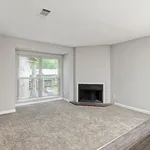 Bright and airy living room with a large window, cozy fireplace, and plush carpet flooring.