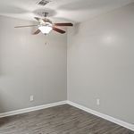 Bright and modern room with sleek wood flooring, neutral gray walls, and a stylish ceiling fan, perfect for a cozy living space.