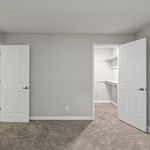 Inviting bedroom featuring plush carpeting and a spacious walk-in closet with modern shelving, enhancing comfort and style.