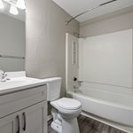 Elegant modern bathroom featuring sleek white fixtures, a spacious bathtub, and stylish cabinetry on a chic wood floor.